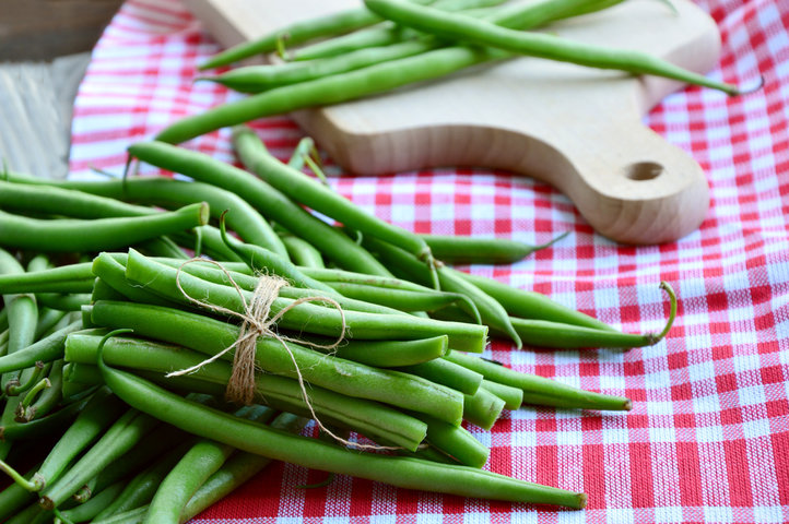 Fresh green beans with a red checkered cloth and cutting board