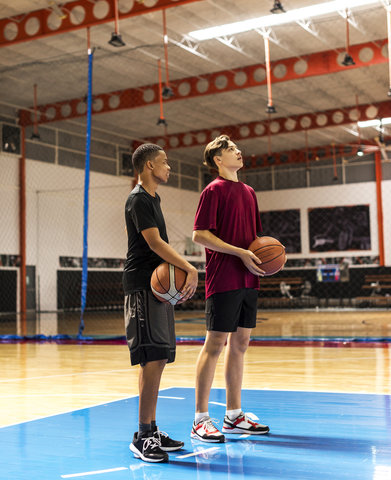 Two young men holding basketballs on basketball court