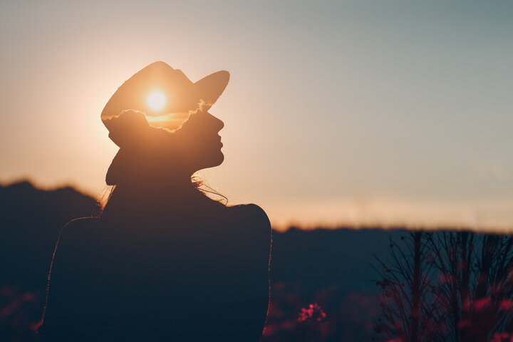 A persons silhouette outside with sun effect on hat